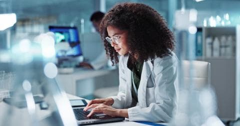 Female researcher working on her laptop in a lab