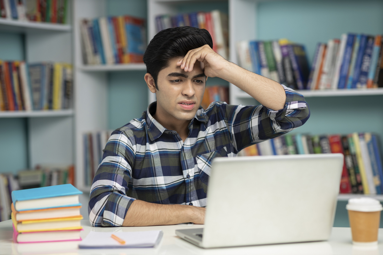 Student staring at laptop, looking confused