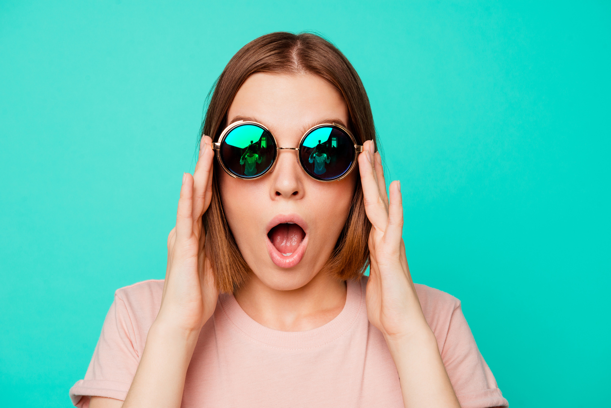 Woman wearing green-tinted glasses, looking shocked