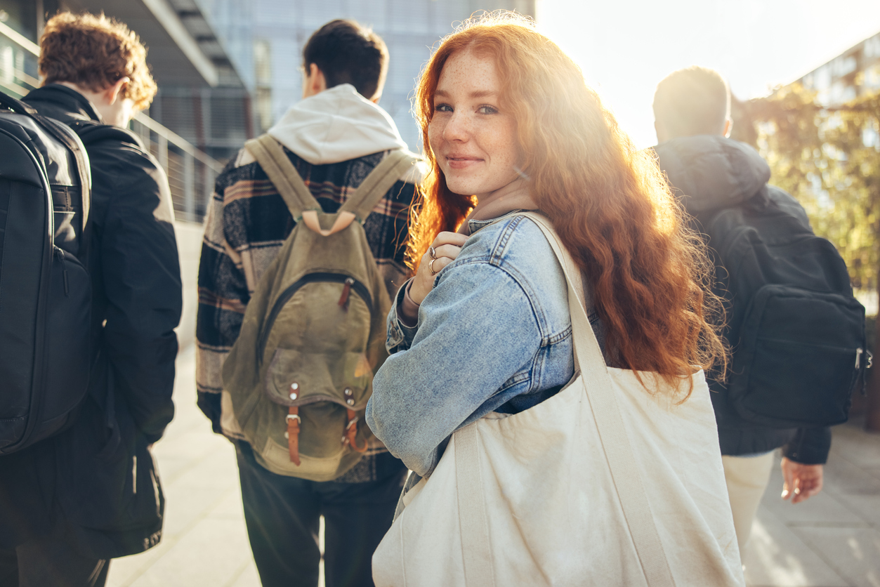 A group of high-school students walking away; one turns back