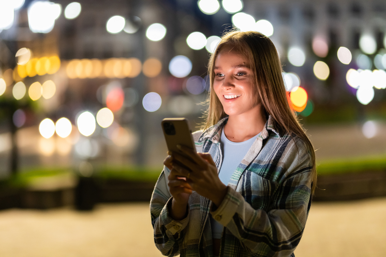 Student out at night, looking at her mobile phone