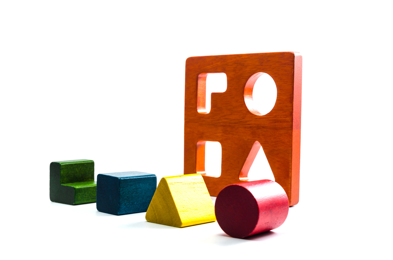 Shape sorter, with wooden shapes lined up in front of it