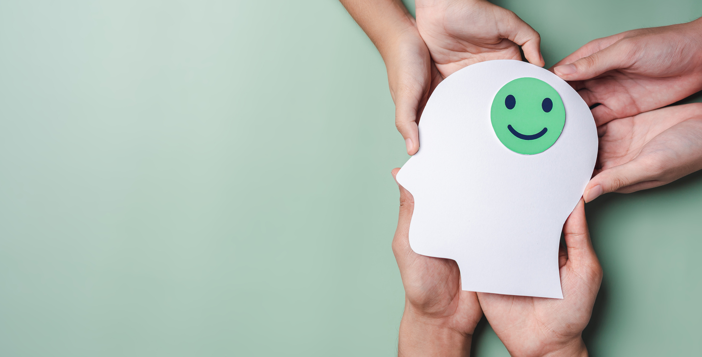 Hands holding a cut-out of a head, with a smiling face on it