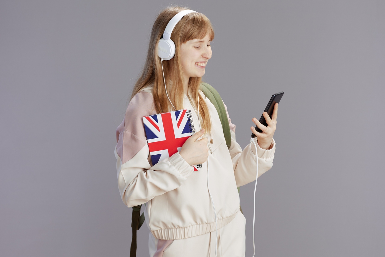 Student holding a Union Jack notebook and smiling at news on phone