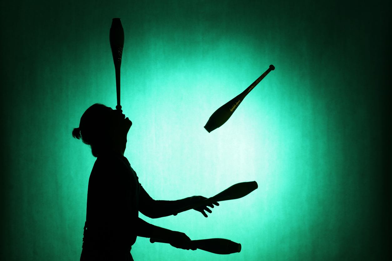 Woman juggling clubs, with one balanced on her nose