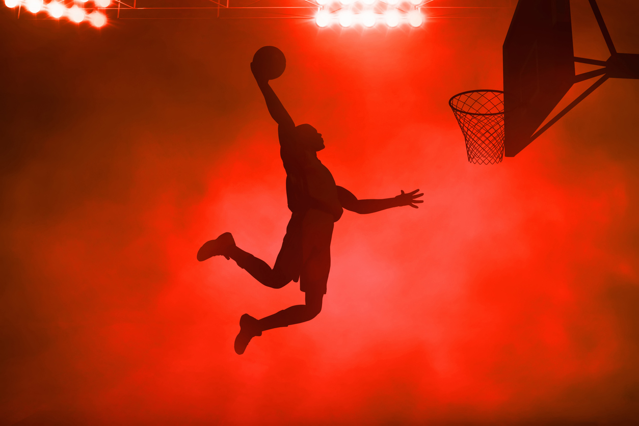 Silhouette of basketball player aiming ball into net