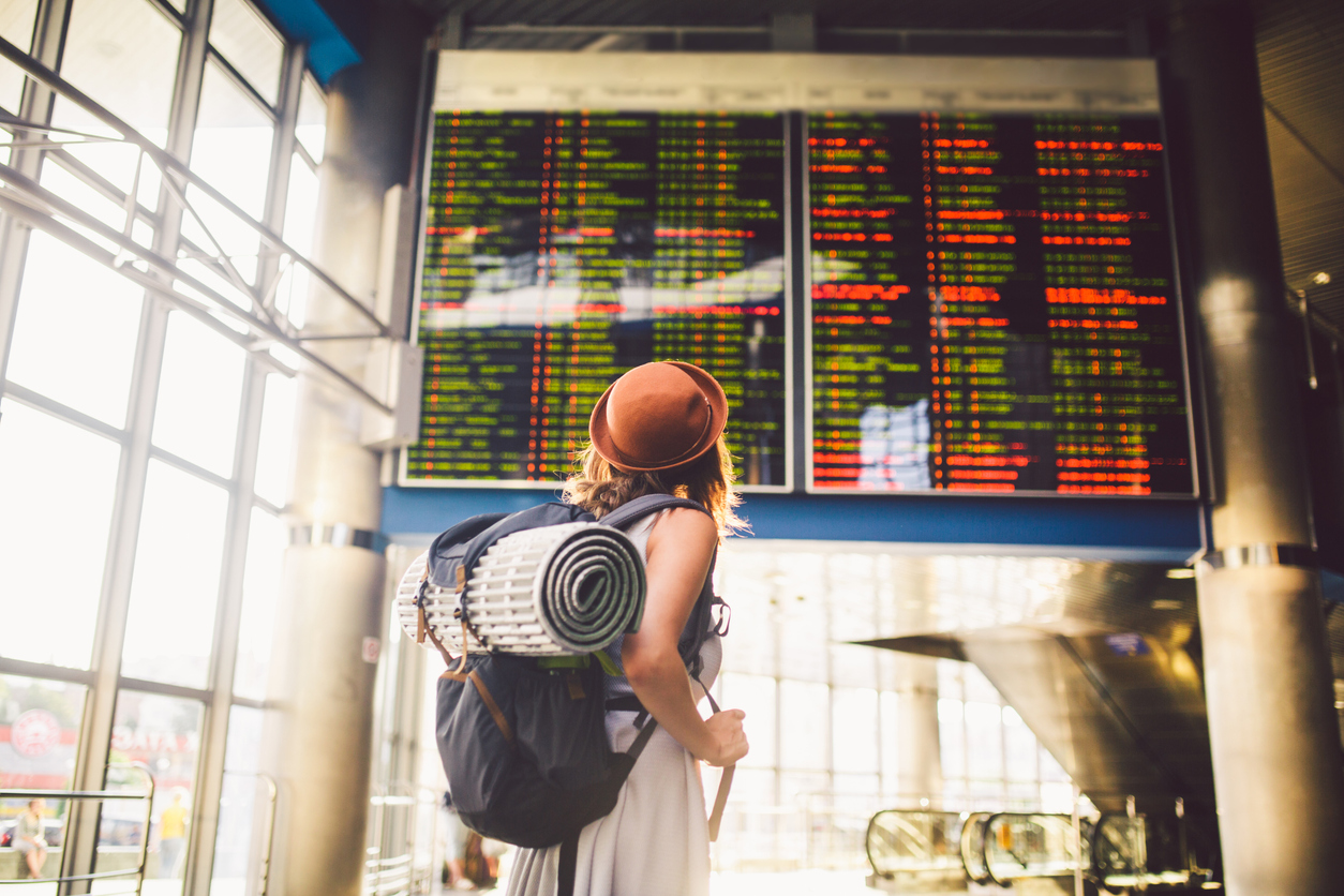 Woman in airport, looking at departures board