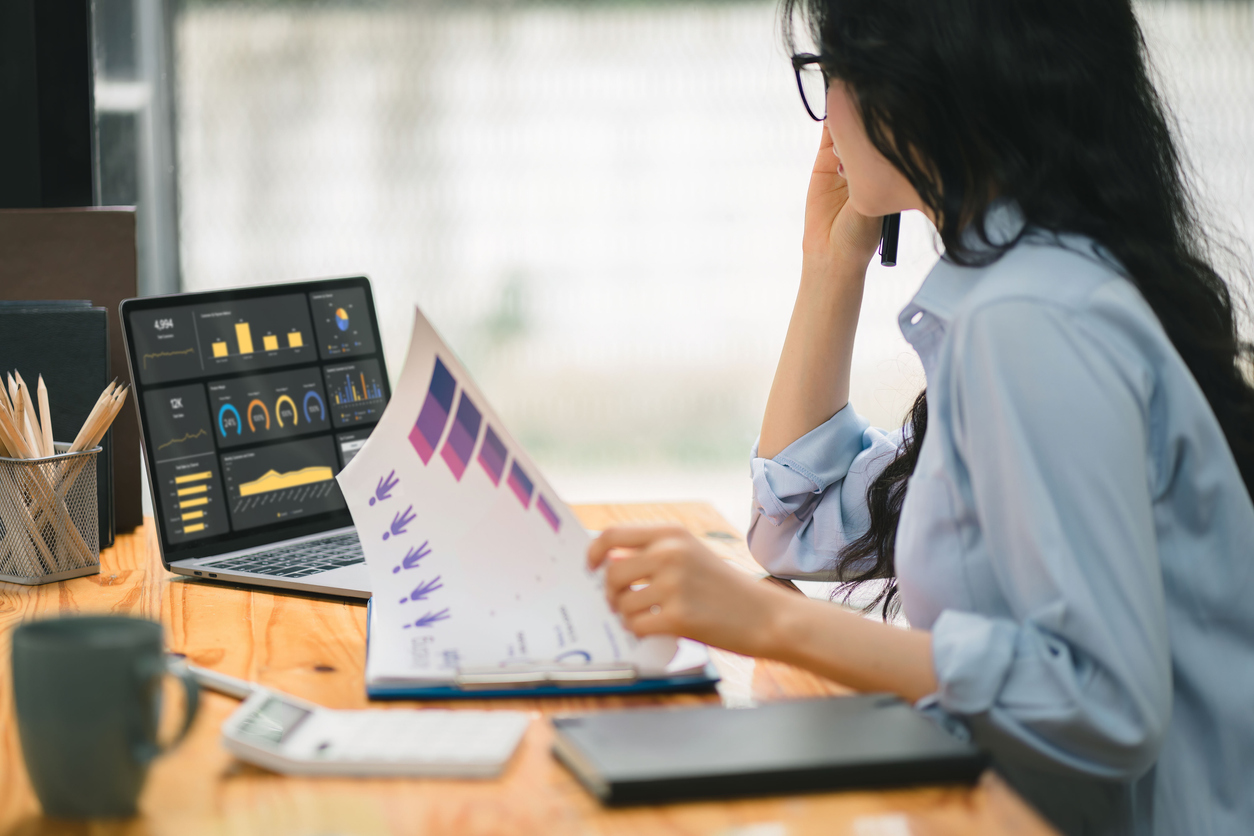 Counsellor, looking at data on a computer and in a paper report