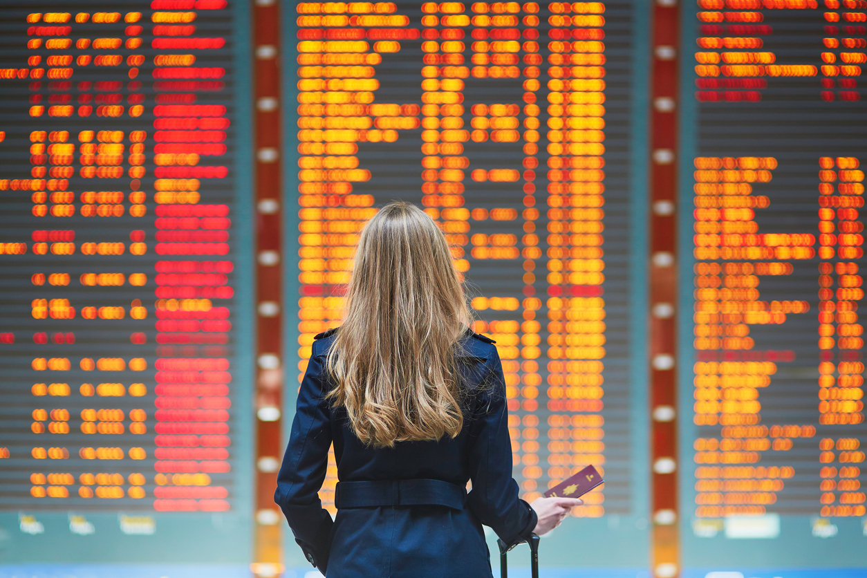 Woman looking at airport departure board