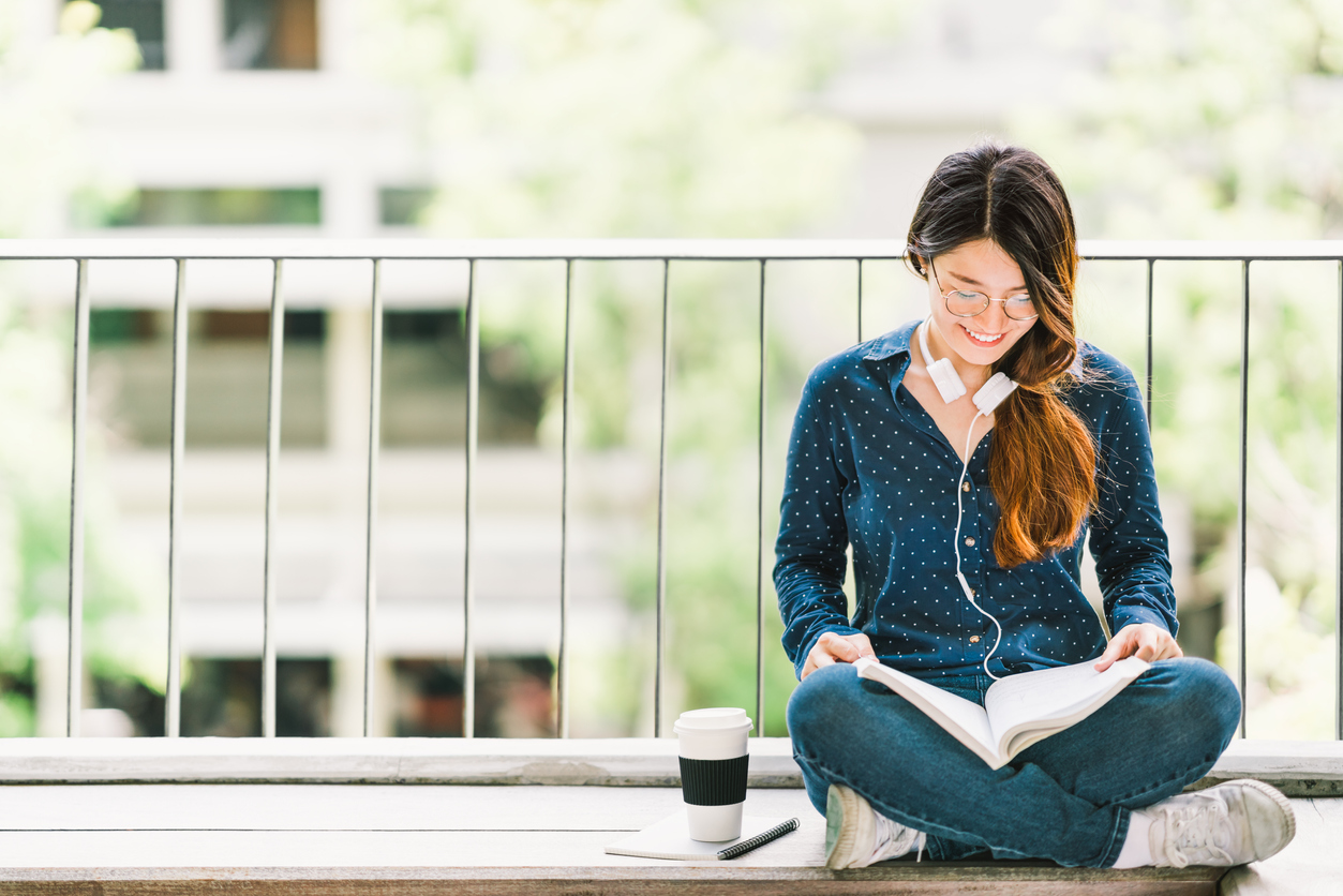 Student sitting on balcony, reading notes