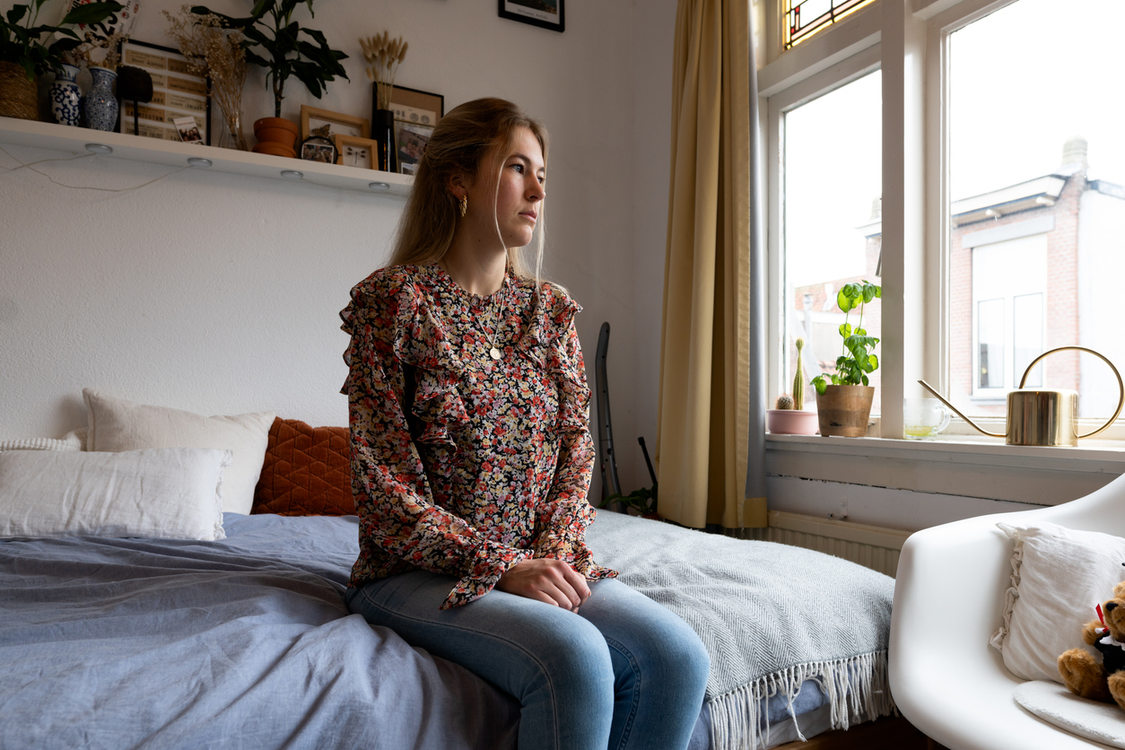 Student in bedroom, looking worried