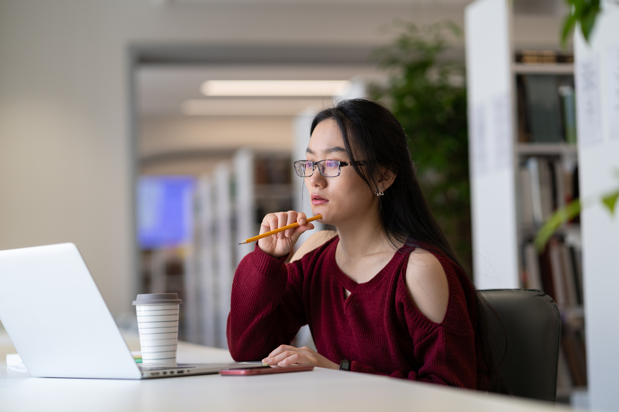 Student sitting at computer, looking thoughtful