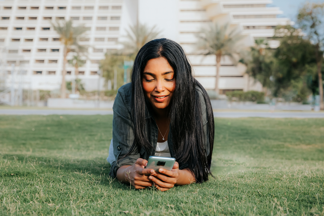 Student in park in Qatar, looking at her phone