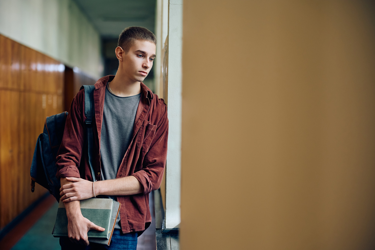 Student standing in corridor, looking sad