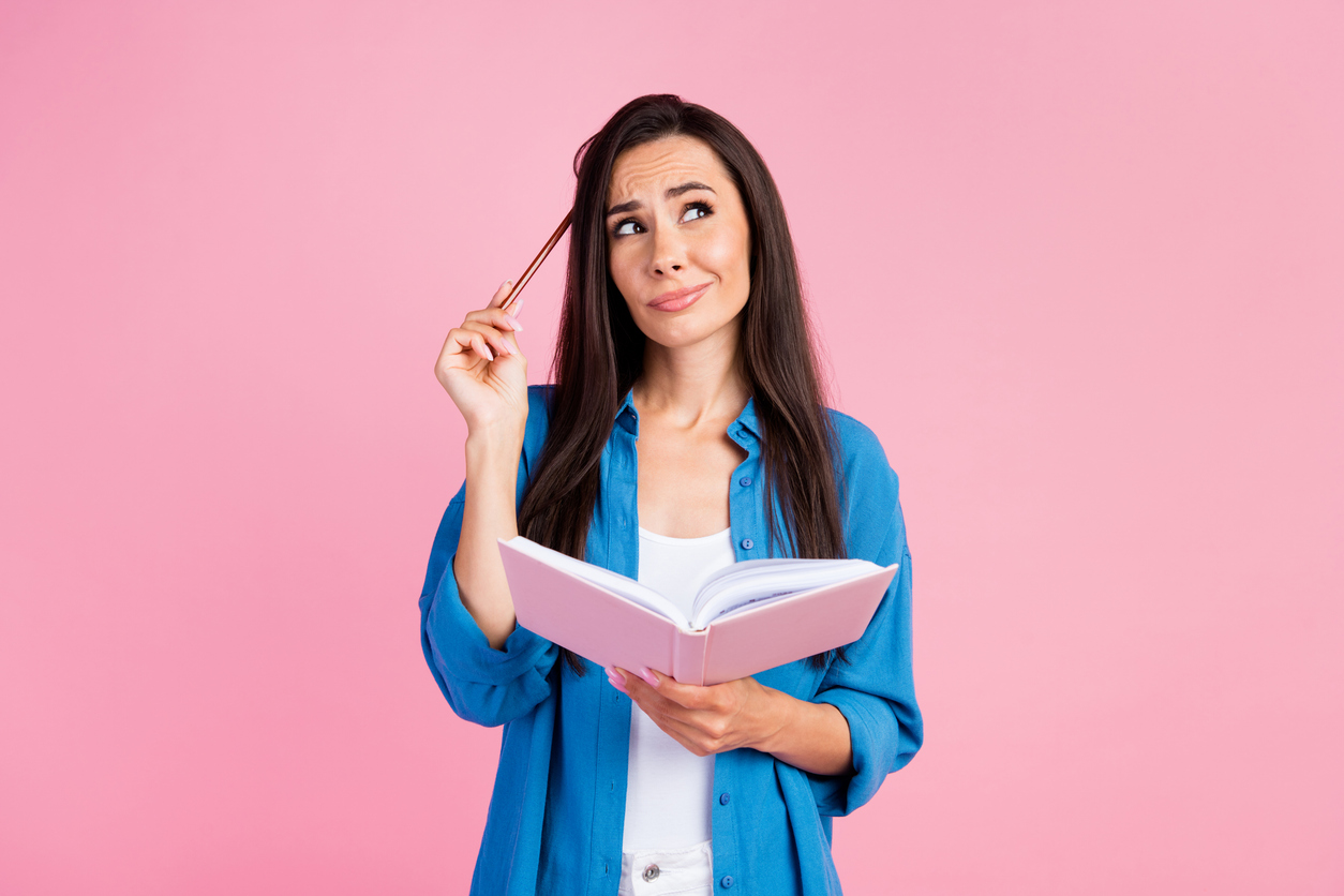 Woman holding open notebook, looking confused