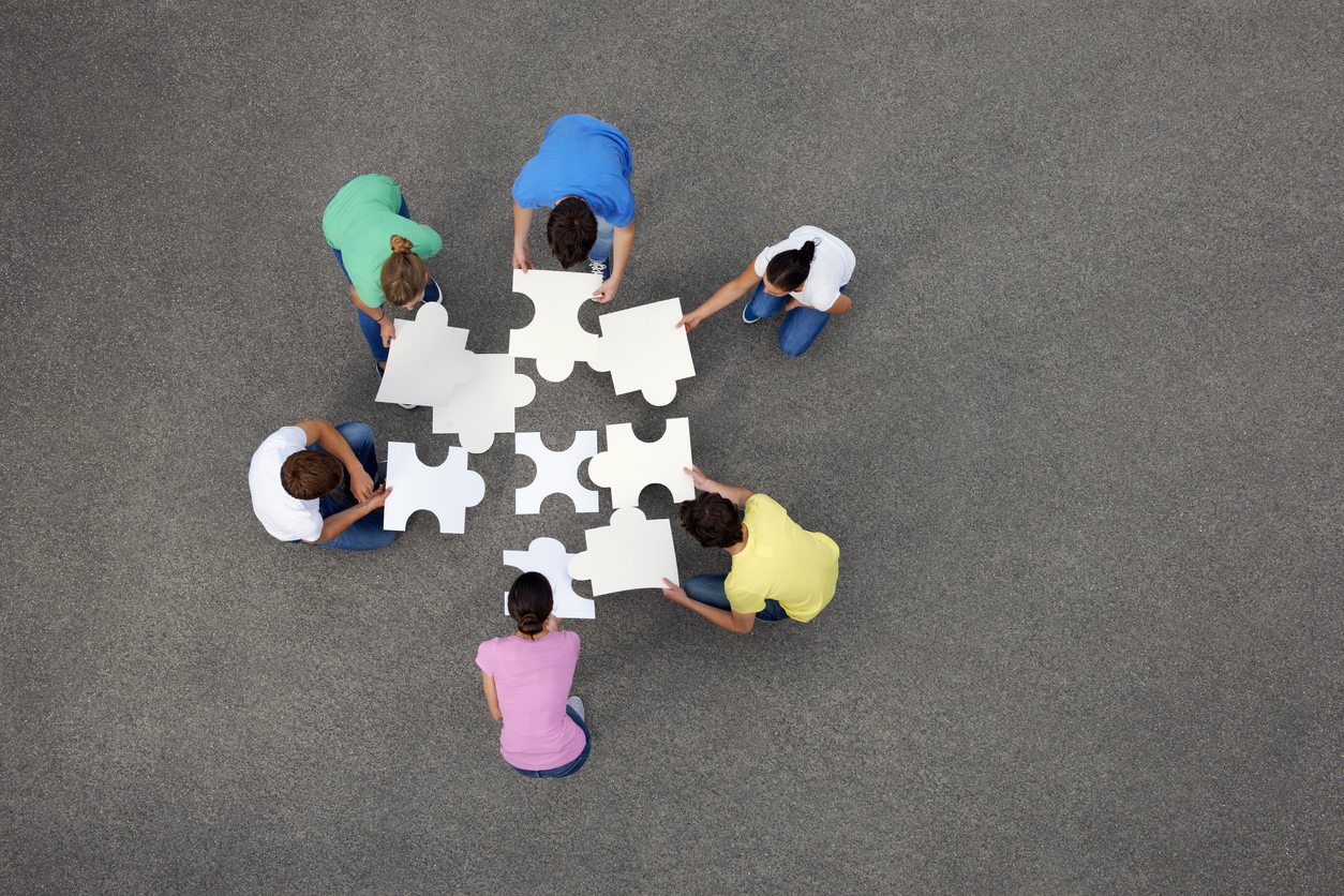 Several people, piecing together a giant jigsaw puzzle