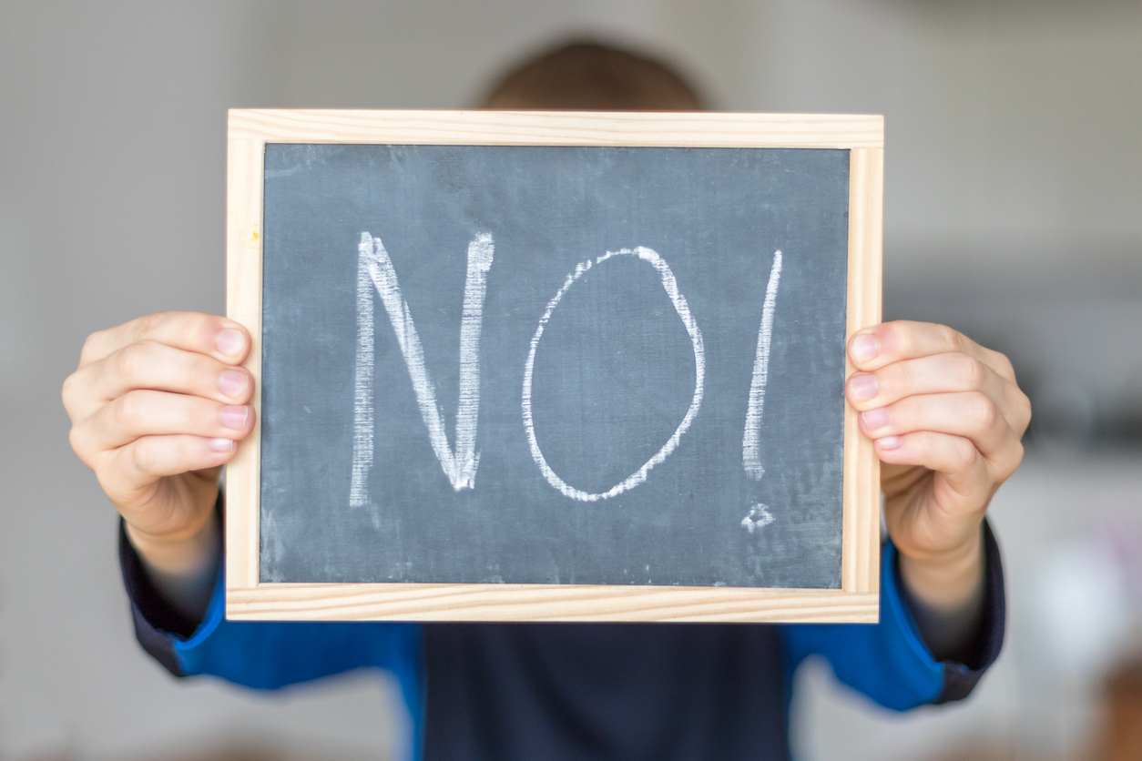 Student holds up mini blackboard, with the word "No!" on it