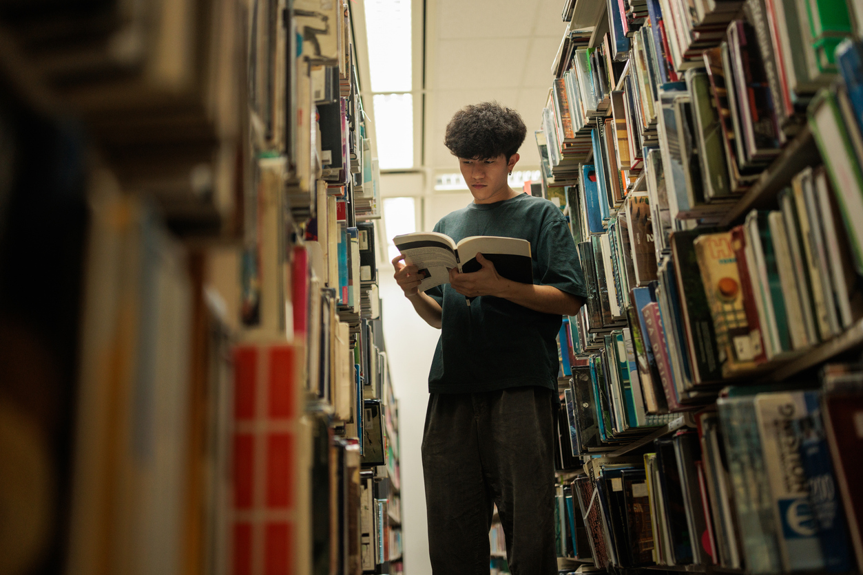 Student standing in library, reading