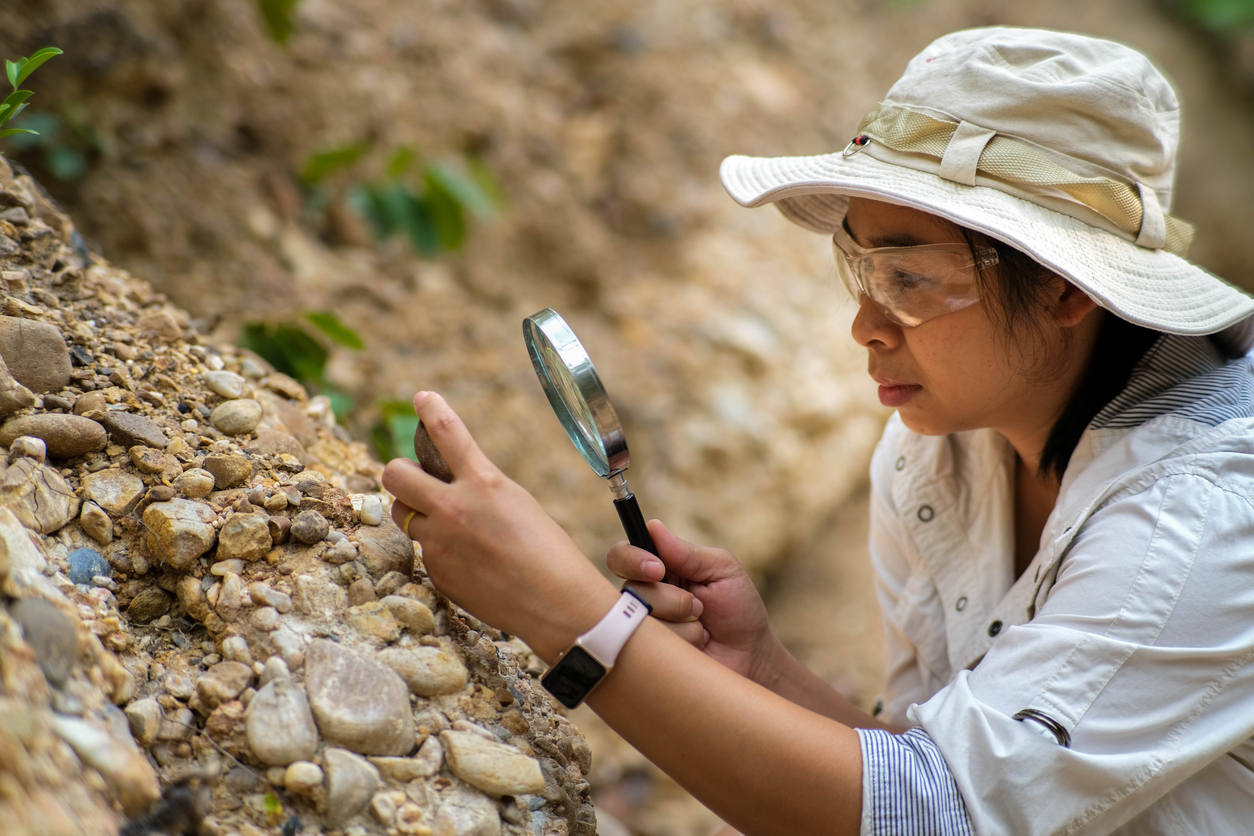 Geologist, studying rock with magnifying glass