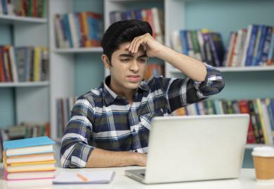 Student staring at laptop, looking confused