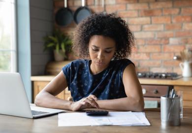 Student, sitting at desk with laptop and calculator