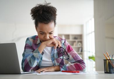 Student at desk, looking pensive