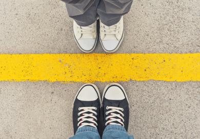 Two sets of feet, standing either side of a thick yellow line