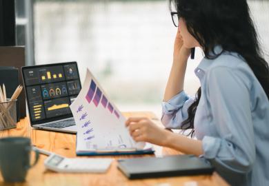 Counsellor, looking at data on a computer and in a paper report