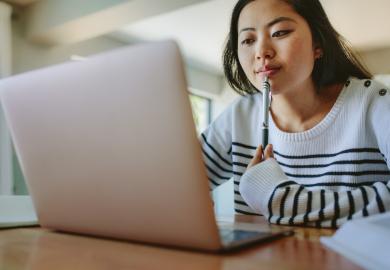 Student, looking pensively at her laptop 