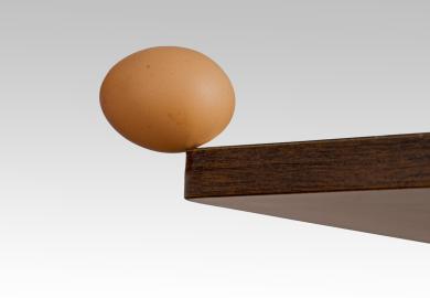 Egg, balanced precariously on the edge of a table