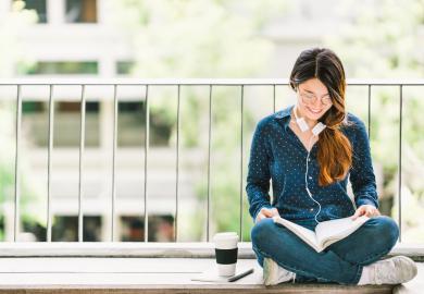 Student sitting on balcony, reading notes