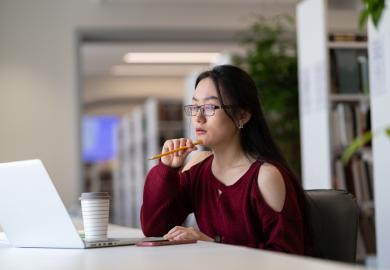 Student sitting at computer, looking thoughtful