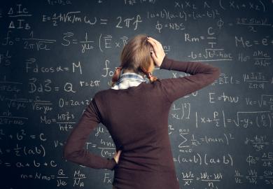 Student looking at complicated maths problem on blackboard