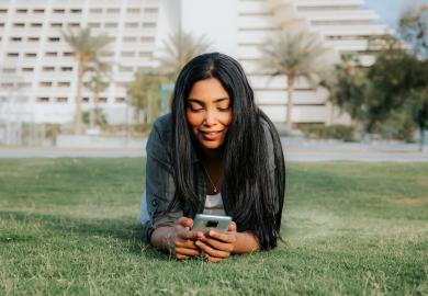 Student in park in Qatar, looking at her phone