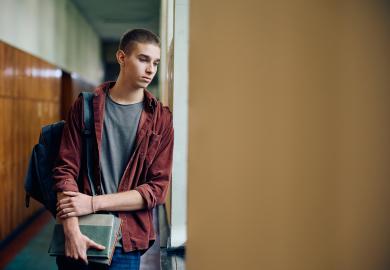 Student standing in corridor, looking sad