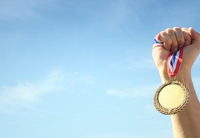 Hand holding up gold medal