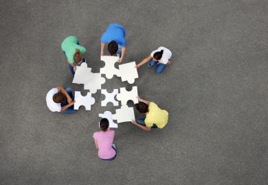 Several people, piecing together a giant jigsaw puzzle