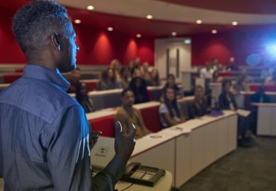 Man delivering a talk to lecture theatre full of students