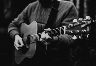 Black and white photograph of folk singer, playing guitar