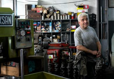 An industrial / factory worker stands by their machine