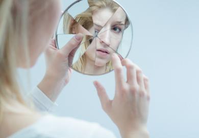 Woman looking in shattered mirror