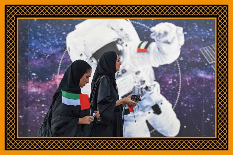 Women walk past an illustration depicting an astronaut with the Emirati national flag outside Mohammed Bin Rashid Space Centre (MBRSC) in Dubai, UAE