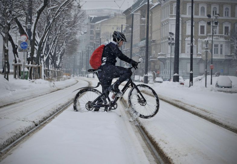 A man rides on his bicycle through the snow covered tram tracks during snowfall in Budapest, Hungary