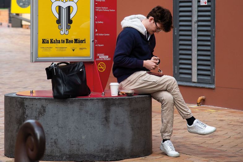 A man sits next to a Maori language sign