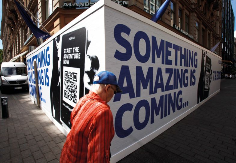 A pedestrian passes advertising hoardings outside Nokia Oyj's flagship mobile phone store in Helsinki, Finland