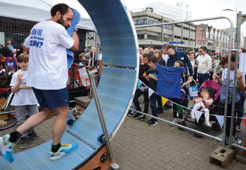 Person running in a a six feet diameter wooden 'hamster wheel' in Southend, UK