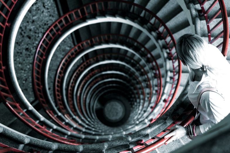 Woman on a spiral staircase looking down in a building to illustrate sight loss struggle