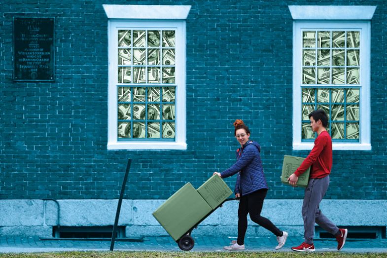 Two people carrying heavy boxes with a building behind with dollar notes filled in the windows behind them.