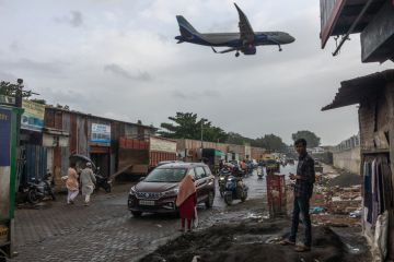 An aeroplane flies over slums in Mumbai