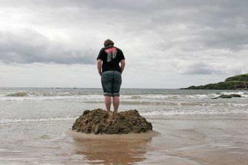 Someone stands on a beach in a small flood defence